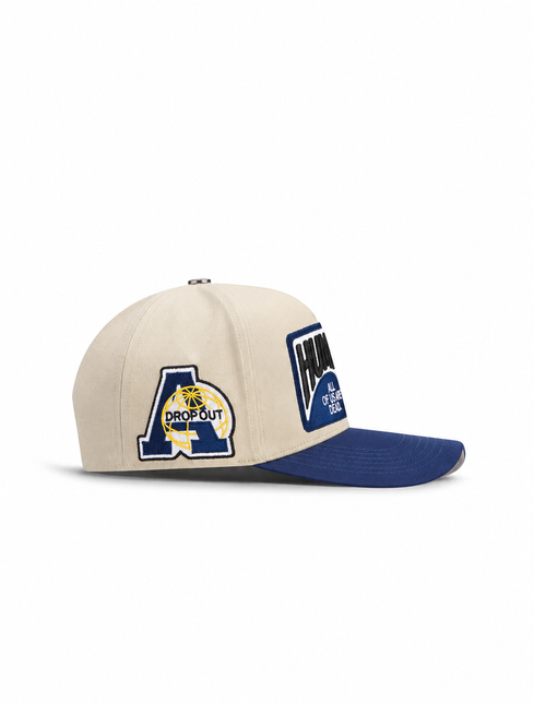 All Human THE CURE cap in cream cotton with a navy blue brim featuring embroidered globe and text patches.