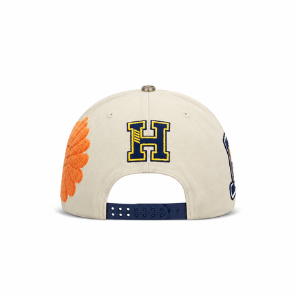 All Human The Cure snapback cap in cream cotton with a navy blue letter H embroidery and a textured orange flower.