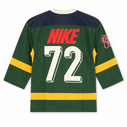 Nike Sportswear Club hockey-style jersey in forest green with navy shoulders, yellow accents, and white 72 graphic.