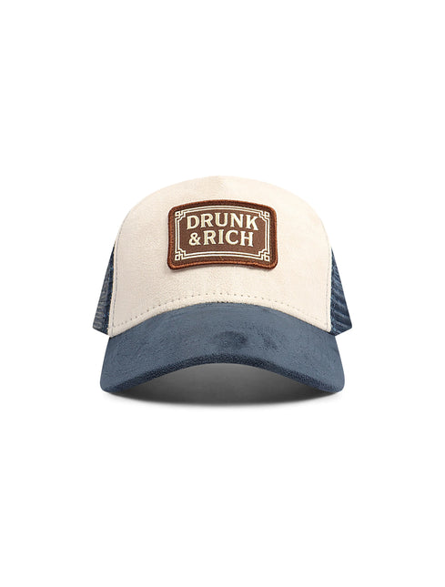 Drunk & Rich trucker hat featuring a cream suede front panel, navy blue suede brim, and navy mesh back with logo patch.
