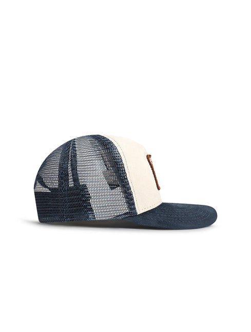 Drunk & Rich trucker hat featuring a cream suede front panel, navy mesh back, navy suede brim, and brown leather logo.