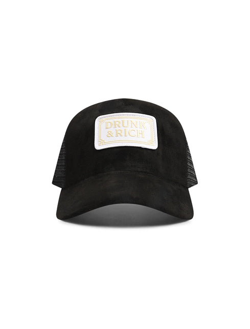 Black suede trucker hat featuring a cream-colored rectangular patch with gold DRUNK & RICH text on a white background.