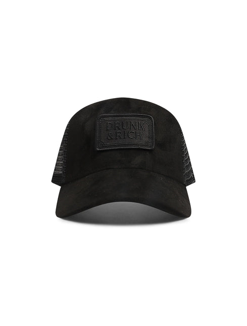 Black Drunk & Rich trucker hat featuring a suede-like front panel, breathable mesh sides, and a matching logo patch.