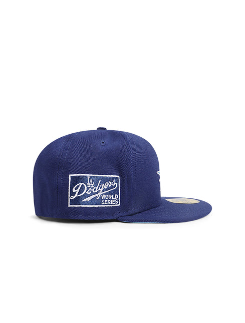 Side view of a navy blue fitted baseball cap with a Dodgers script patch on the side panel.