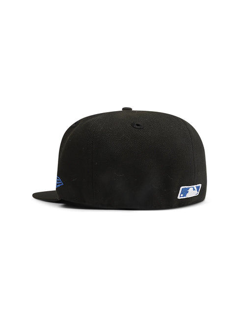 Back view of a black fitted baseball cap with a small MLB logo patch and a blue embroidered detail on the side.