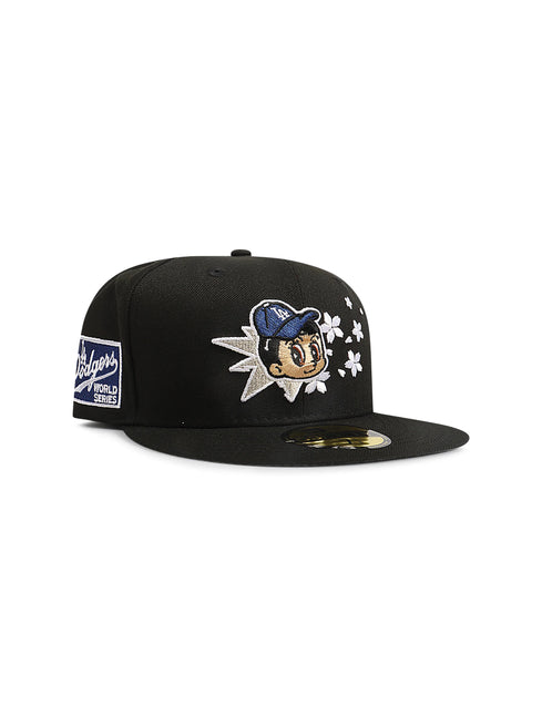 Black fitted baseball cap with an embroidered cartoon character surrounded by stars and a Dodgers patch on the side.