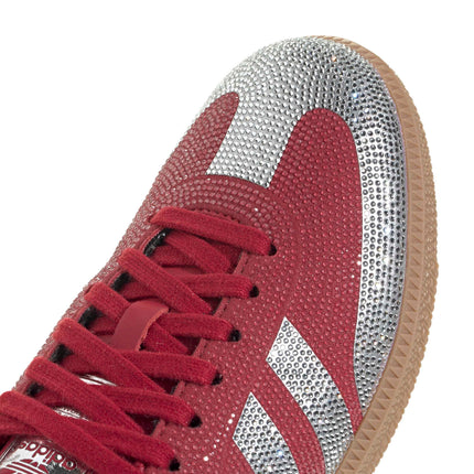 Close-up of a red suede Adidas Samba OG sneaker embellished with sparkling silver rhinestone panels and a gum sole.
