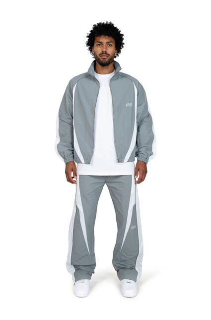 EPTM Legacy tracksuit in light grey and white featuring a zip-up nylon jacket and matching loose-fit joggers on a man.