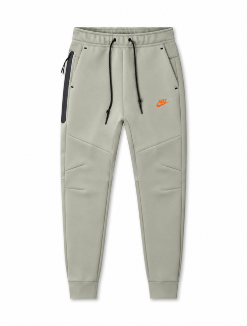 Nike Men's Tech Fleece joggers in light army green with black drawstrings, side zip pocket, and orange logo detail.