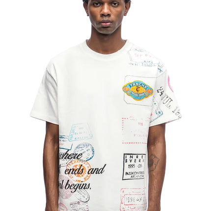 White cotton crewneck t-shirt from Trnchs featuring a collage of colorful vintage travel stamp graphics on the front.