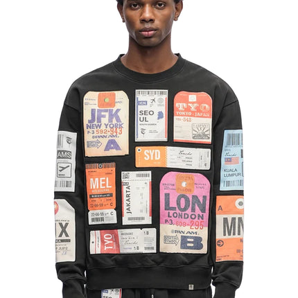 Black cotton crewneck sweater by Trnchs featuring a collage of colorful vintage-style international travel tags.