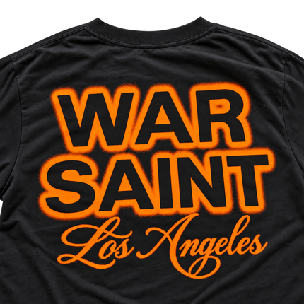 Black cotton t-shirt with screen-printed Warsaint Los Angeles graphic in bold neon orange halftone lettering.