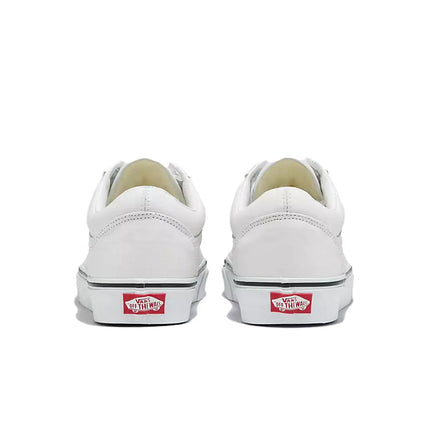 Rear view of white leather Vans Old Skool sneakers featuring red branded heel tabs on a plain white background.